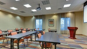 A conference room with long tables and chairs, a podium, and a projector screen. - Fairfield Inn Suites Dunn I 95 (Dunn)