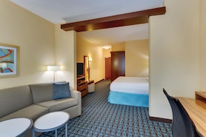 A hotel room with a sofa, two small tables, a bed, a desk, and a mirror. - Fairfield Inn Suites Dunn I 95 (Dunn)