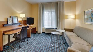 A hotel room with a wooden desk, a TV, a sofa, a small table, and a patterned carpet. - Fairfield Inn Suites Dunn I 95 (Dunn)
