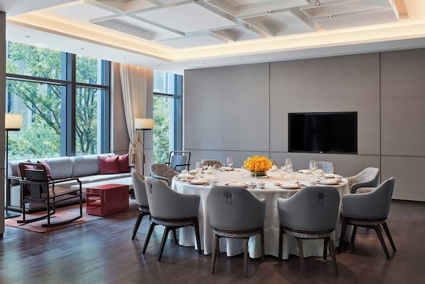 A modern dining room with a round table set for six, a sofa with cushions, and a large window with curtains. - Sheraton Shanghai Fengxian (Shanghai)