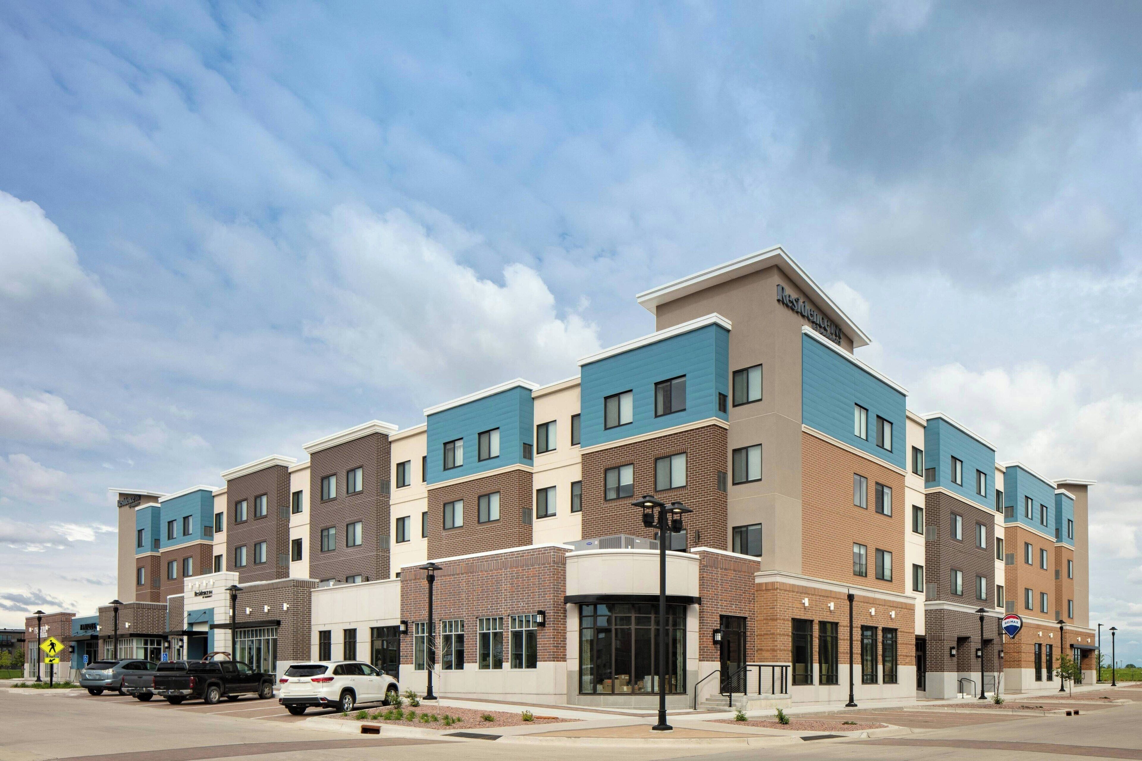 A multi-story hotel with a modern design, featuring a mix of brick and blue facade, large windows, and a prominent entrance.