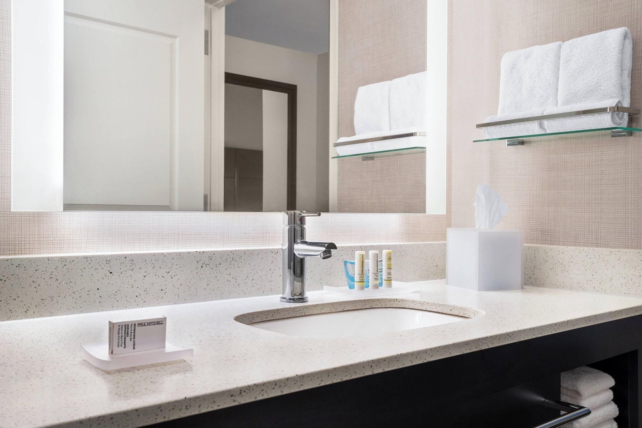 A modern bathroom with a large mirror, a sink, and a towel rack.