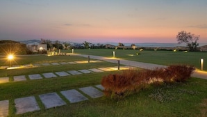 A landscaped garden with a paved walkway, stone steps, and illuminated outdoor lighting.