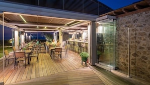 An outdoor patio area with wooden flooring, seating arrangements, and a bar counter.