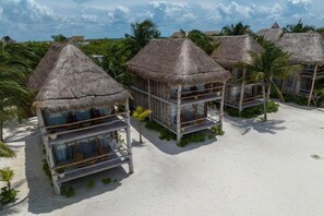 A resort with thatched-roof bungalows, each with a balcony and surrounded by palm trees. - Blue Holbox Hotel (Isla Holbox)