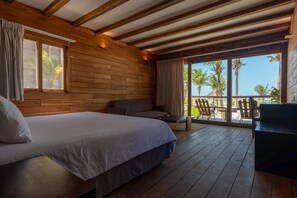 A wooden cabin room with a bed, a sofa, and a balcony with chairs. - Blue Holbox (Isla Holbox)