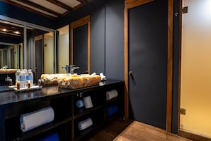 A bathroom with a dark wall, a wooden door, a mirror, and a towel rack. - Blue Holbox (Isla Holbox)