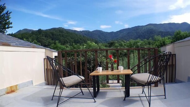 A balcony with two chairs and a table, overlooking a mountainous landscape. - Lebua Corbett (Salt)