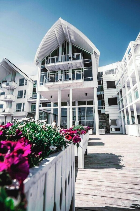 Un edificio moderno con un tetto curvo e numerosi balconi.