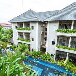 A multi-story hotel with balconies, a swimming pool, and lush greenery. - Bali Hotel (Phnom Penh)