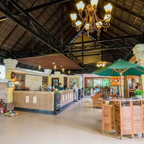 A reception area with a counter, a chandelier, and a bell service booth. - Bali Hotel (Phnom Penh)