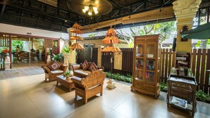 A spacious lobby with traditional wooden furniture, a large wooden cabinet, and hanging lamps. - Bali Hotel (Phnom Penh)