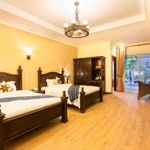 A hotel room with two wooden beds, a chandelier, a wardrobe, and a view of the outdoors through a glass door. - Bali Hotel (Phnom Penh)