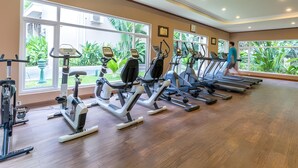 A gym with multiple treadmills, exercise bikes, and a person walking on a treadmill. - Bali Hotel (Phnom Penh)