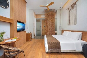 Une chambre d’hôtel moderne équipée d’un lit, d’une télévision, d’un bureau avec une chaise et d’une cloison en osier.