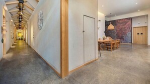 Un pasillo moderno de hotel con techo de madera, un área de comedor con pared estampada y una gran pieza decorativa en la pared.