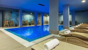 An indoor swimming pool with lounge chairs and a patterned wall. - Ores Boutique Hotel (Bansko)