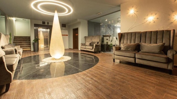 A modern lobby with a central light fixture, a staircase, and a sofa. - Ores Boutique Hotel (Bansko)