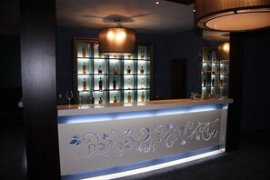 A bar area with a counter, shelves of bottles, and a decorative light fixture. - Ores Boutique Hotel (Bansko)