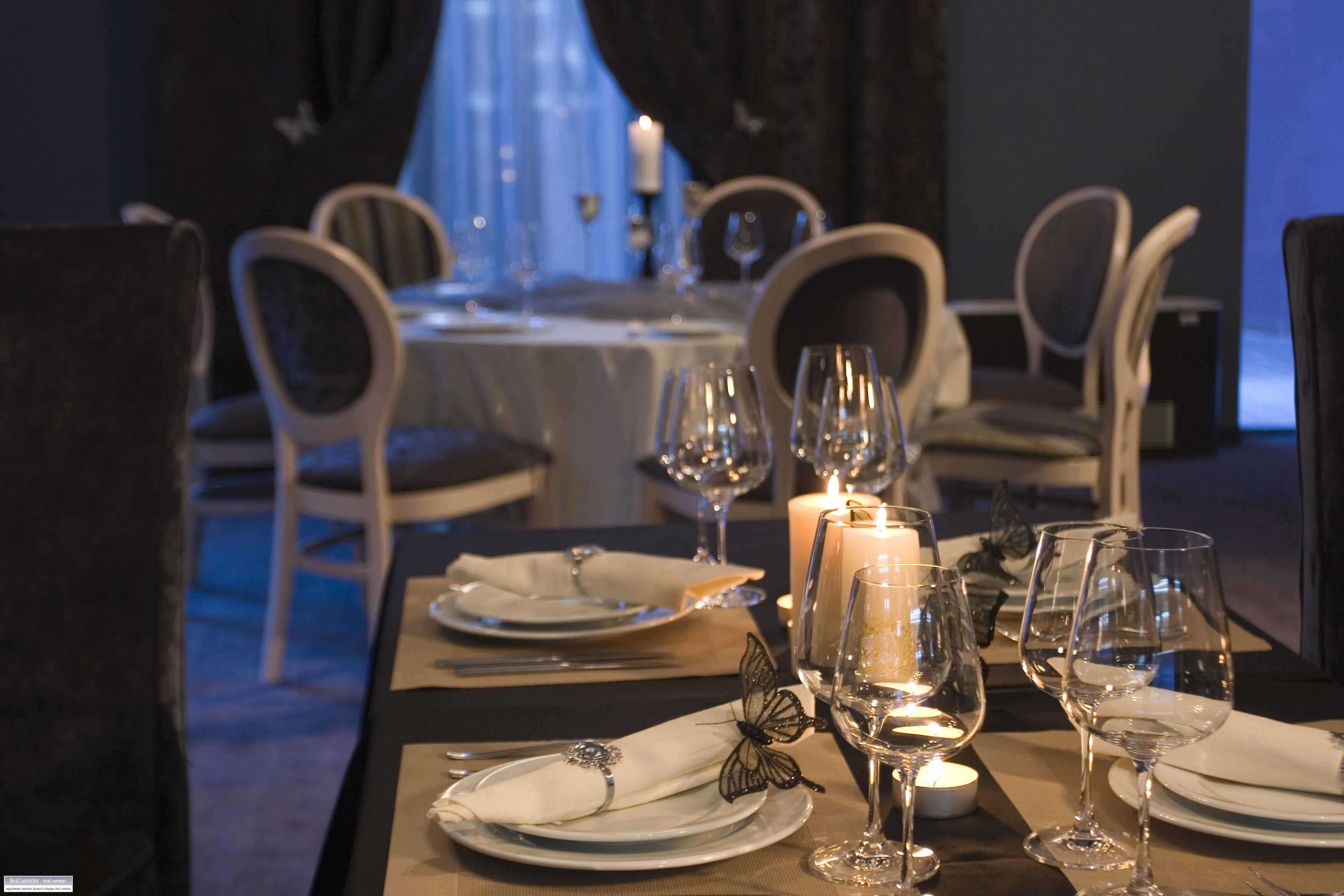 A dining table set for a meal with candles, wine glasses, and plates.