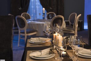 A dining table set for a meal with candles, wine glasses, and plates. - Ores Boutique Hotel (Bansko)