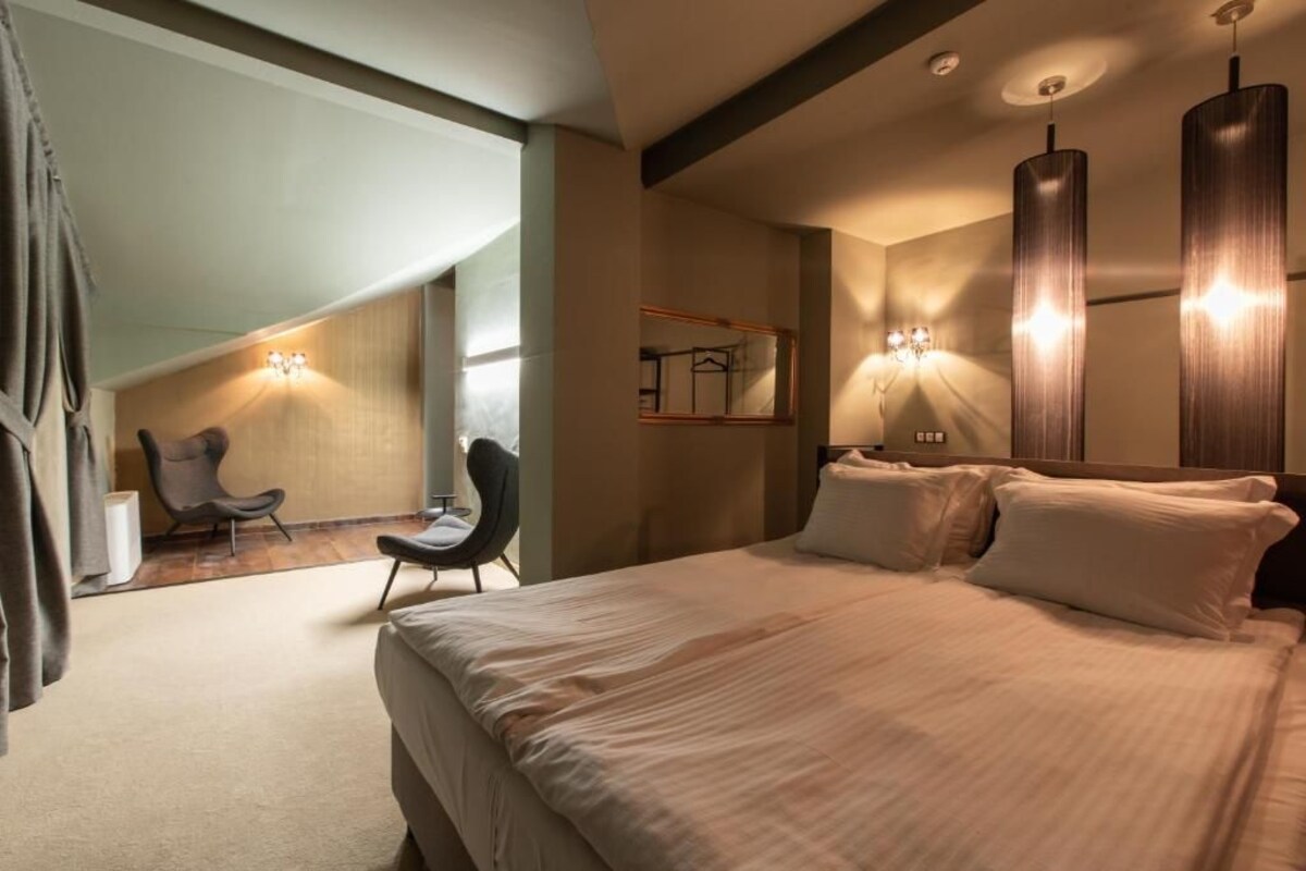 A modern hotel room with a large bed, a chair, and a mirror.
