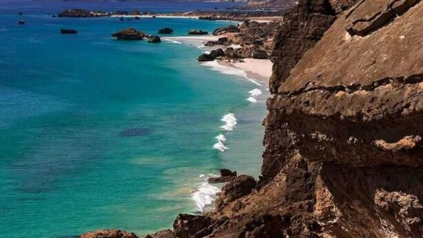 A coastal landscape with rocky cliffs, clear turquoise waters, and distant mountains. - Ramee Dream Resort Seeb (Seeb)