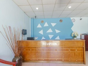 A reception desk with a 'RECEPTION' sign, a clock, and a decorative wall with geometric patterns. - D View Hotel (Mersing)