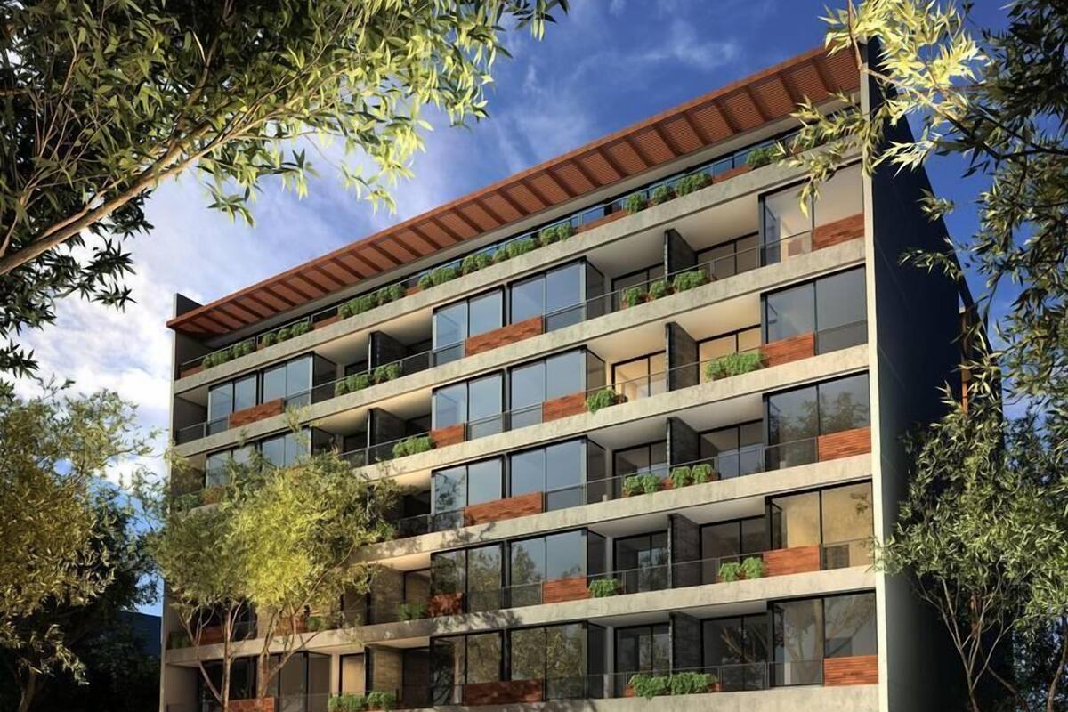 A multi-story building with balconies, a car entrance, and a staircase leading to the entrance.