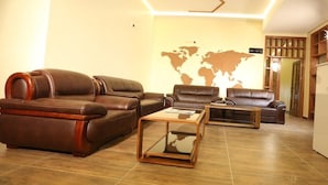 Un salón moderno con sofás de cuero, una mesa de centro de vidrio y un mapa mundial en la pared.