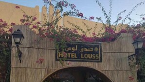 L’entrée d’un hôtel, avec une enseigne indiquant « HÔTEL LOUISS » en arabe.