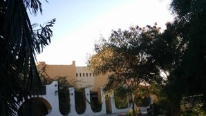Une route sinueuse menant à un bâtiment à la façade blanche et orné de plusieurs arcades.