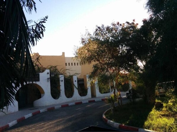 Una carretera curva que conduce a un edificio con fachada blanca y varios arcos.
