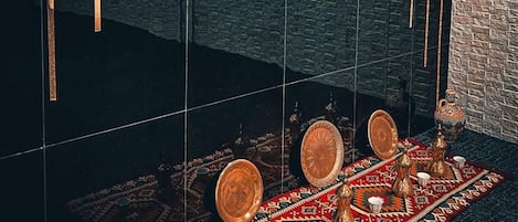 A modern room with a black tiled wall, a patterned rug, a traditional tea set, and an air conditioning unit.