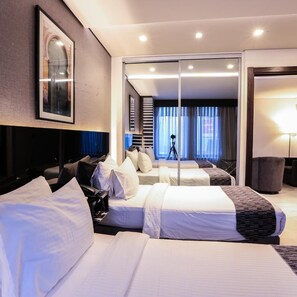 A hotel room with two beds, a large mirror, a camera tripod, and a view of the outside through the window. - Khuttar Furnished Apartments (Amman)