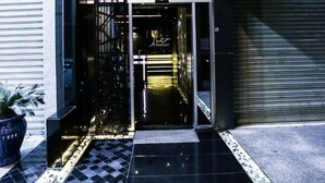 A hotel entrance with a modern design, featuring a glass door and a sign with illuminated text. - Khuttar Furnished Apartments (Amman)