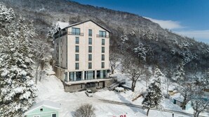 A multi-story hotel with a modern design, located in a snowy mountainous area. - Aurora Resort by One Hotels (Tsaghkadzor)