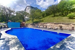 A swimming pool with lounge chairs and a building in the background. - Aurora Resort by One Hotels (Tsaghkadzor)