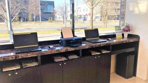 Een receptiebalie met twee laptops, een printer en een vaas met bloemen.