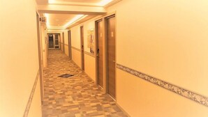 Een hotelgang met patroon vloeren, deuren en een decoratieve rand aan de muren.