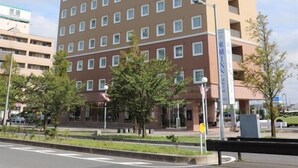 Een hotel met meerdere verdiepingen, met een gelijke gevel, en een rij ramen en balkons.