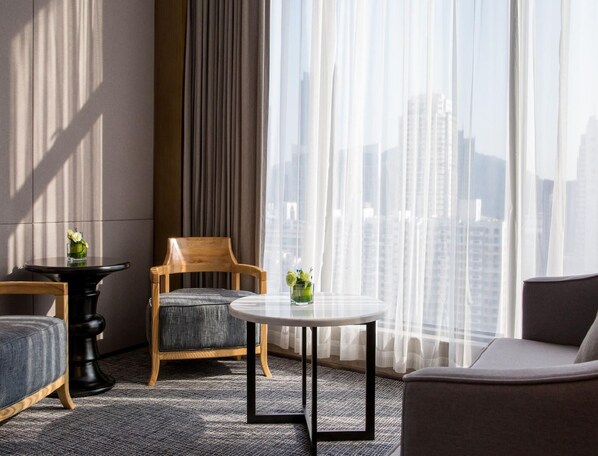 A modern hotel room with a city view, a round table, two chairs, and a sofa. - Xiamen Zenith Hotel (Xiamen)