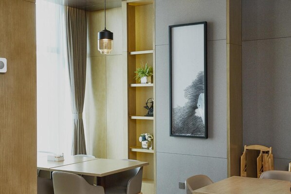 A modern dining area with a wooden table, chairs, a hanging light fixture, and a framed artwork on the wall. - Xiamen Zenith Hotel (Xiamen)