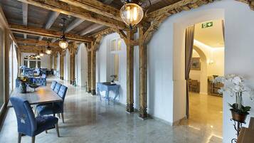 A spacious hotel lobby with a long dining area featuring blue upholstered chairs and a wooden table.