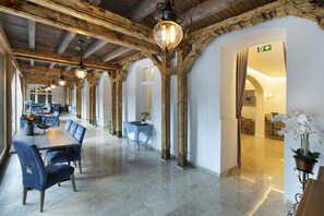 A spacious hotel lobby with a long dining area featuring blue upholstered chairs and a wooden table. - Hotel Caraiman (Sinaia)