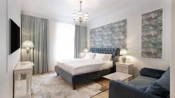 A modern bedroom with a large bed, bedside tables, a sofa, and artwork on the walls.