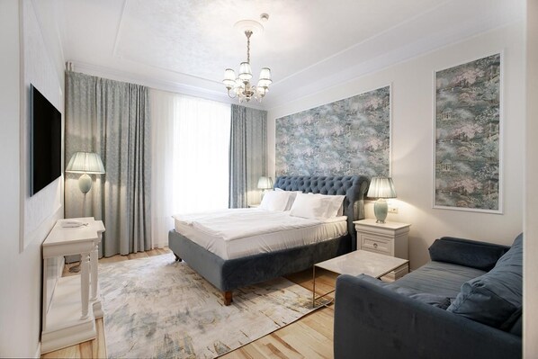 A modern bedroom with a large bed, bedside tables, a sofa, and artwork on the walls. - Hotel Caraiman (Sinaia)
