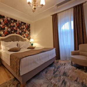 A bedroom with a bed, a chair, a chandelier, a floral wall, and a window with curtains. - Hotel Caraiman (Sinaia)