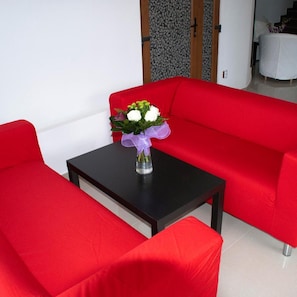 Un sofá rojo con una mesita y un florero.