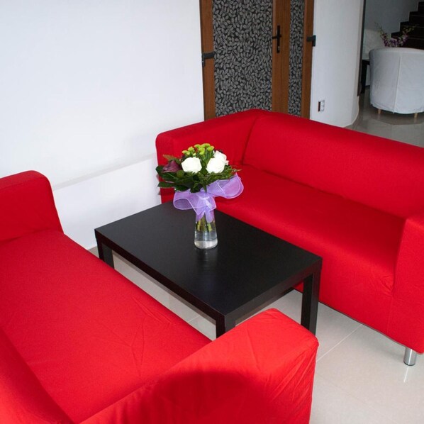 A red sofa set with a small table and a vase of flowers. - Otopeni (Otopeni)